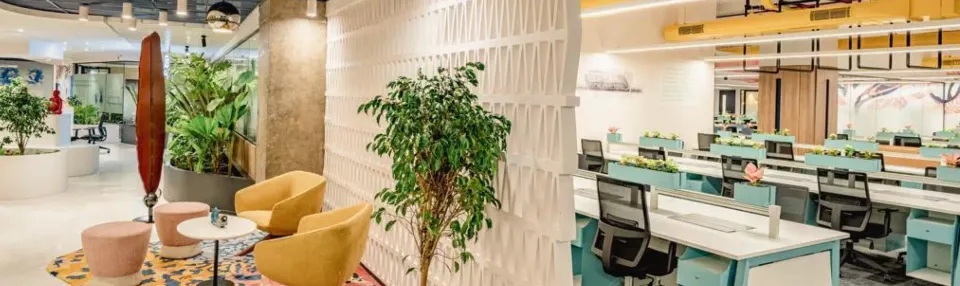 Office interior with desks, plants, and lounge seating.